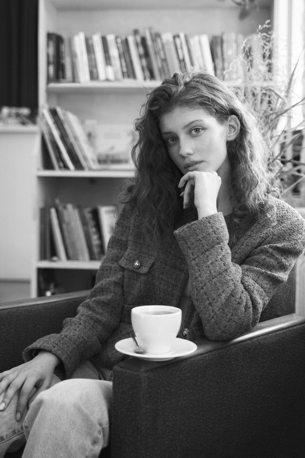 A woman resting in an armchair with a cup of coffee