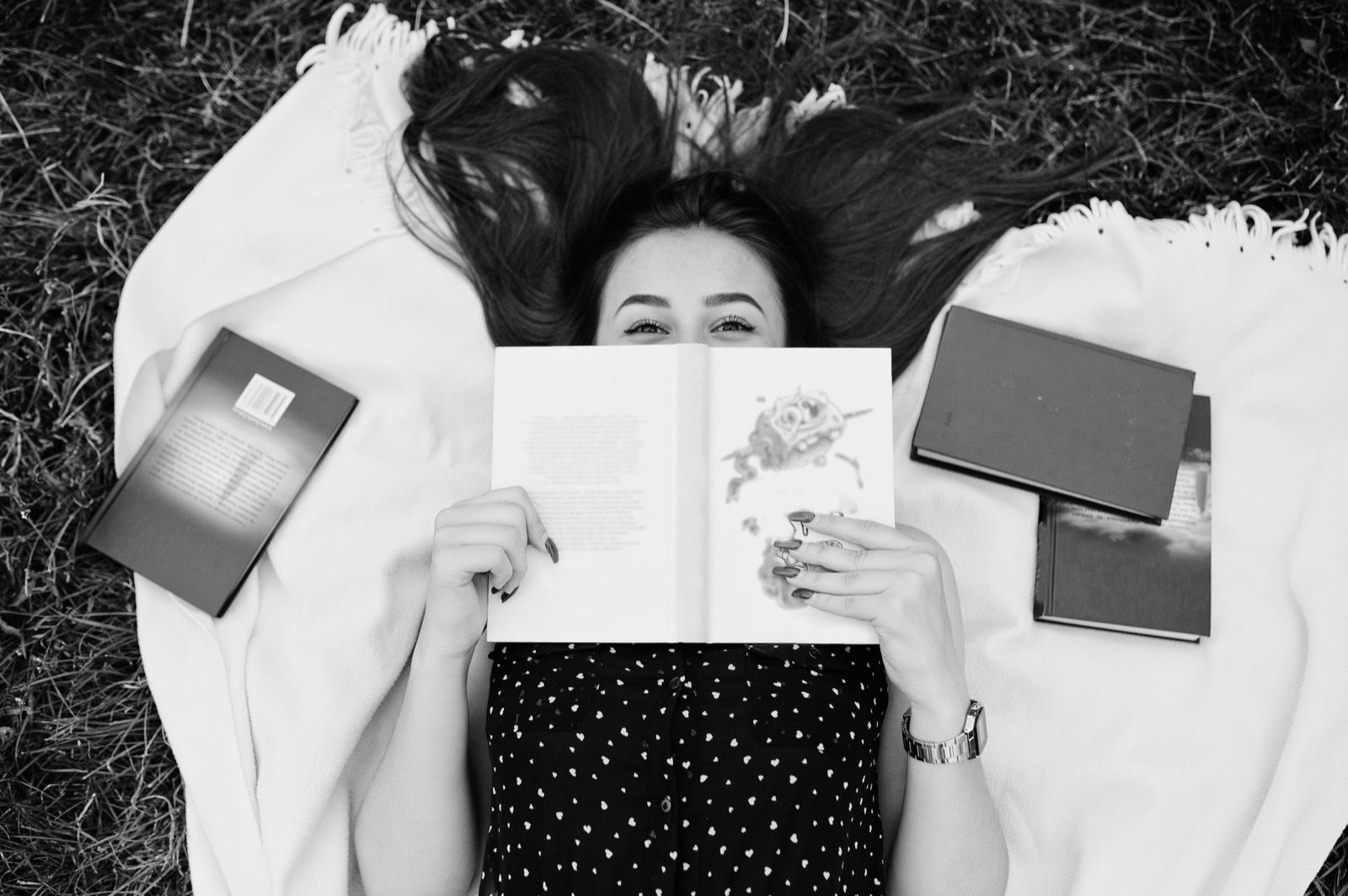 A woman lying in the grass with an open book over her face